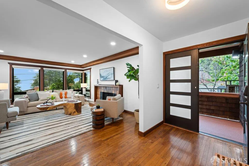 Bright living room with hardwood floors, a striped rug, and a unique wood coffee table. A sliding glass door leads to an outdoor deck.
