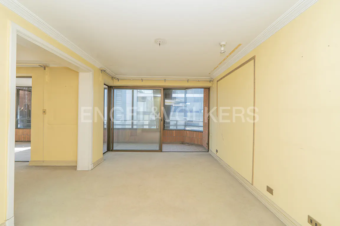 Empty room with yellow walls and beige carpet. Sliding glass doors lead to a balcony with city views.