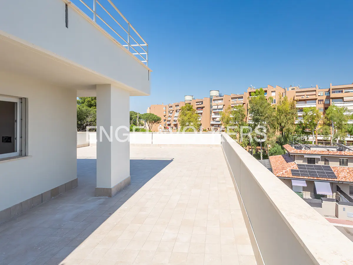 Spacious white rooftop terrace with tiled flooring, overlooking a neighborhood with trees and apartment buildings.