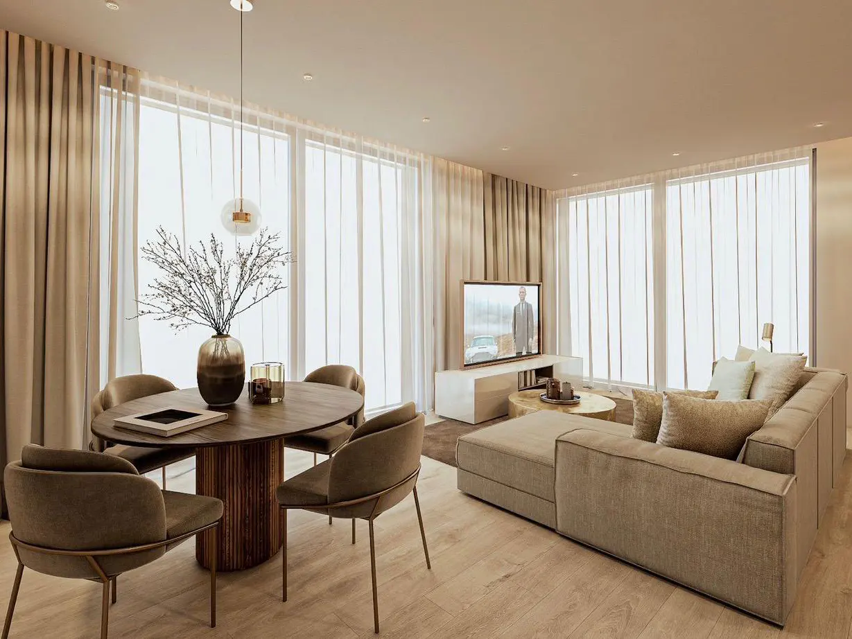 A modern living and dining area with a brown oval table, chairs, and a beige sectional sofa. Large windows with sheer curtains provide natural light.
