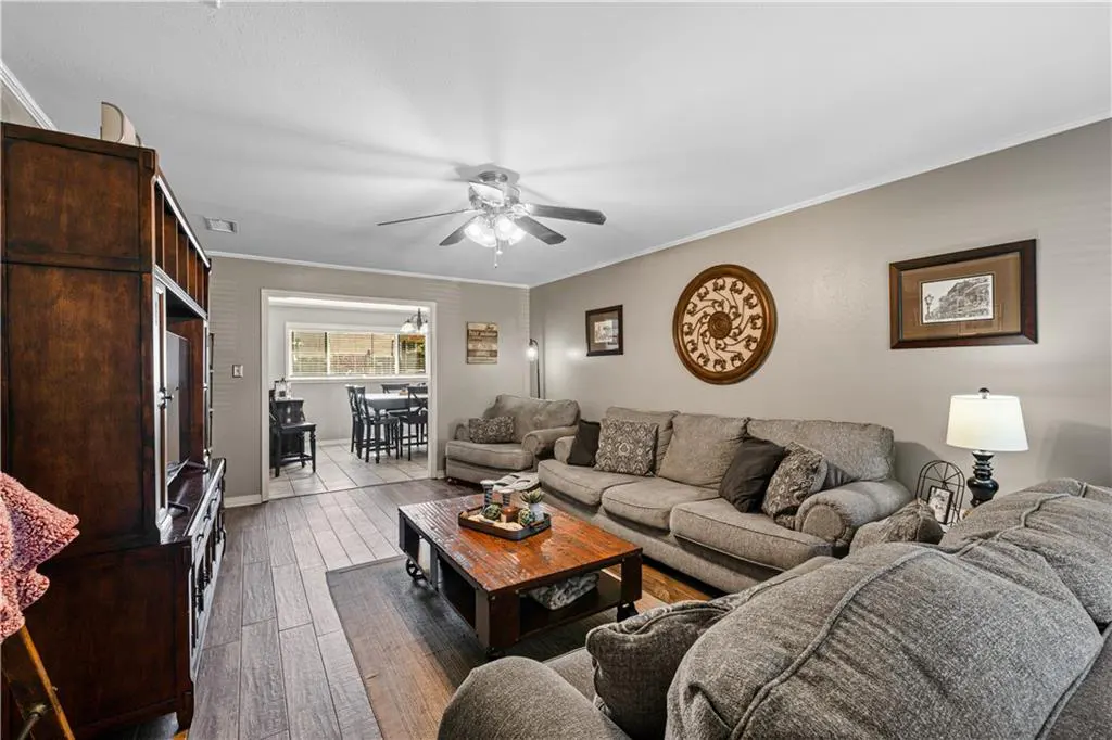 Living room with gray sofa, wooden coffee table, and view into a dining area with tile floors and neutral walls.
