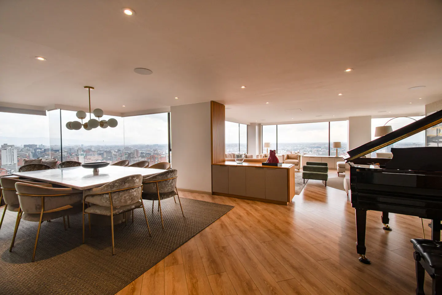 Open-concept living space with a dining table, piano, and city views from large windows.
