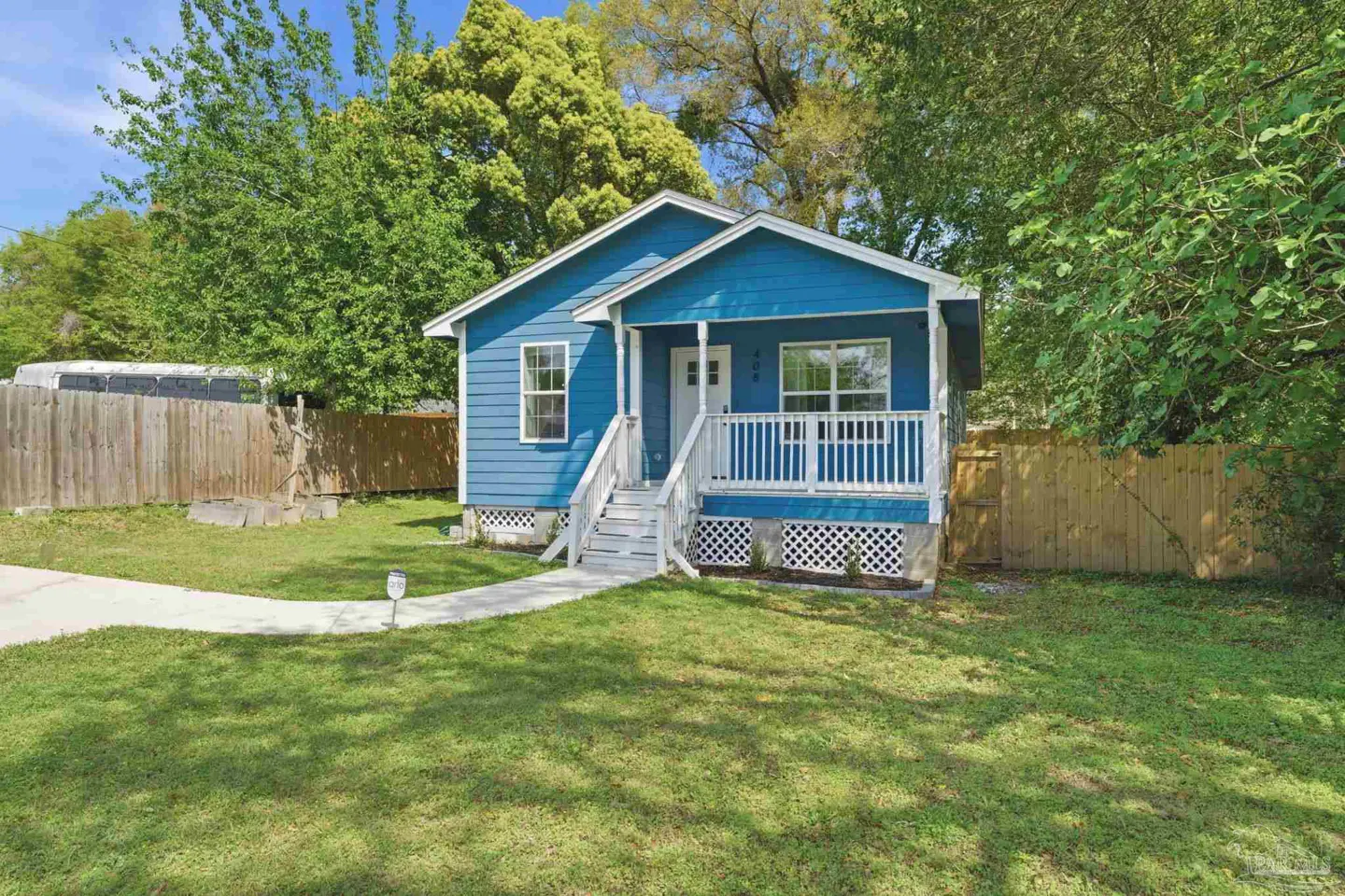 Exterior of a blue, one-story house with a white porch and green lawn.