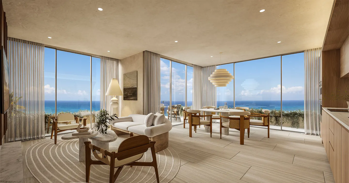 Modern living room with white sofa, wooden chairs, and dining area, featuring floor-to-ceiling windows overlooking the ocean.