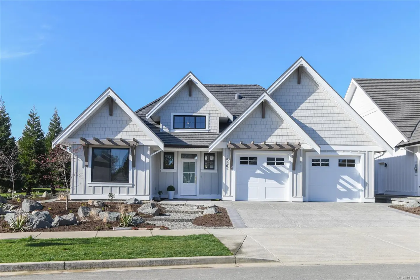 A light gray house with white trim, a gray roof, and a two-car garage on a sunny day.