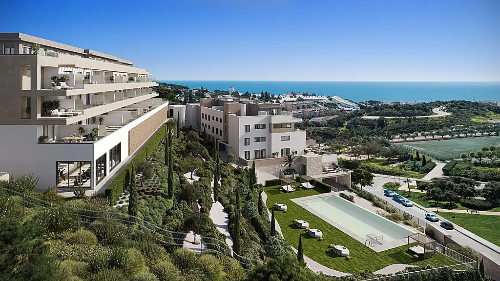 Luxury apartments overlook the ocean. A pool and green space sit below the building on a hillside.