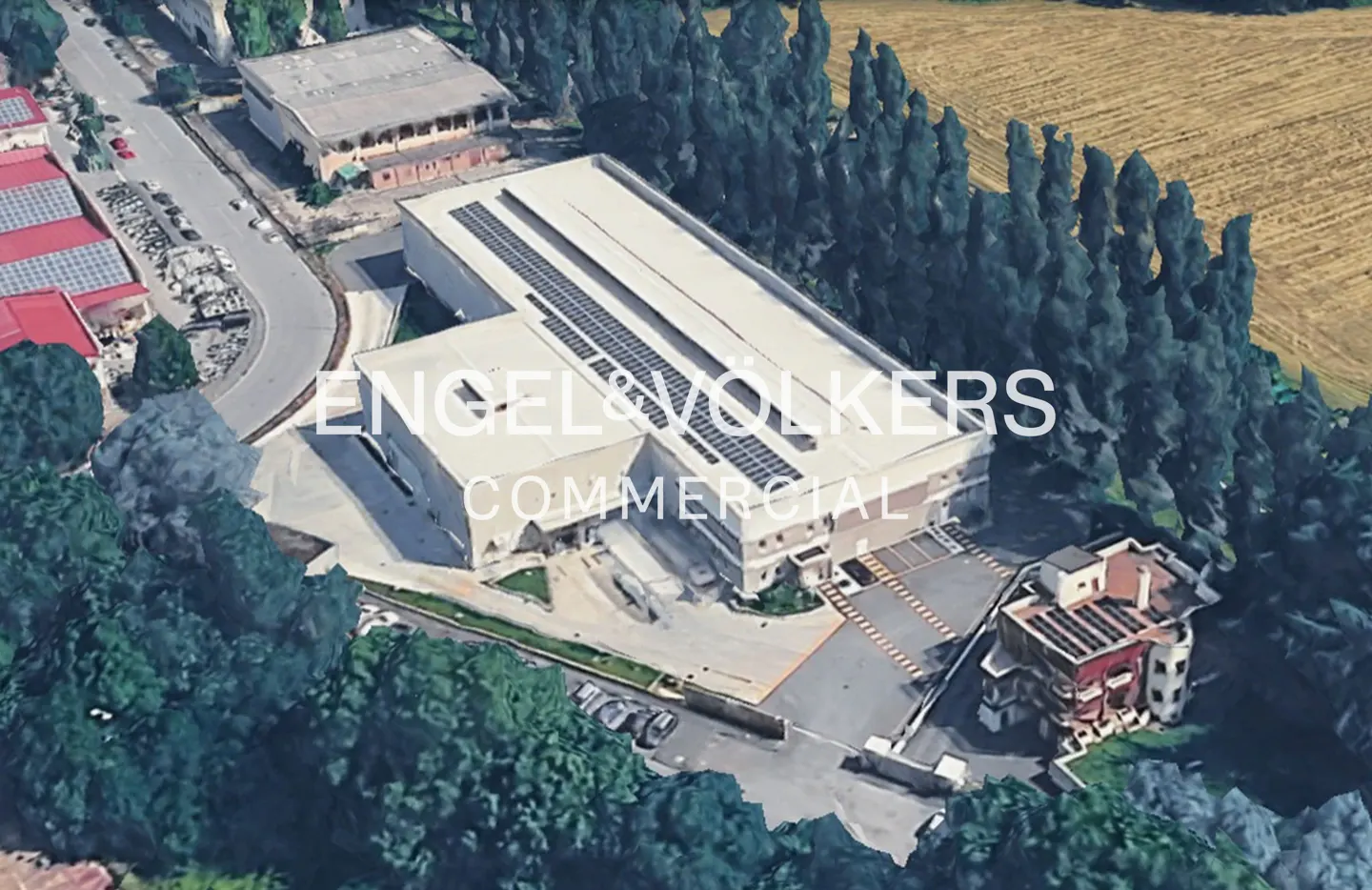 Aerial view of an Engel & Volkers commercial property with solar panels on the roof, surrounded by trees and greenery.