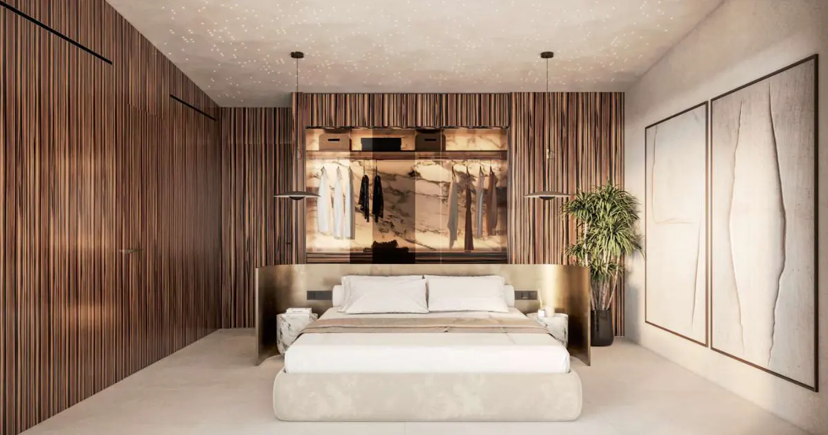 Bedroom with a king bed, wood paneled walls, and a walk-in closet. Two framed artworks are on the right wall.