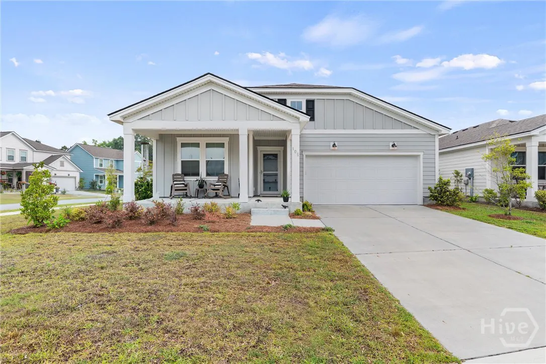 A one-story, light gray house with a white garage door and a covered porch with two rocking chairs.