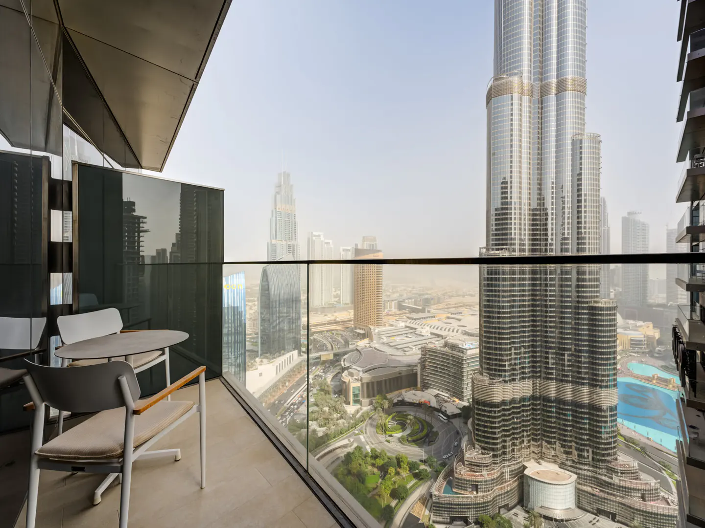 Balcony view of Dubai skyline featuring the Burj Khalifa. Table and chairs sit on the patio.