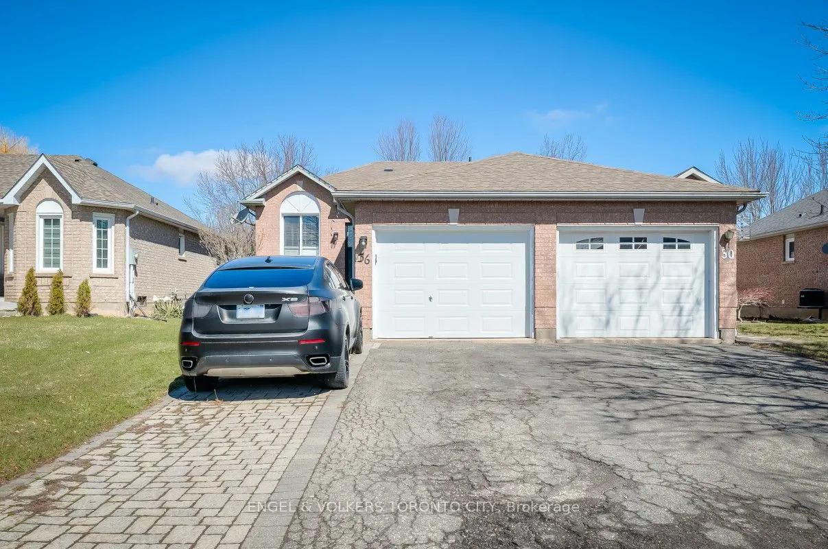 A brick house with a two-car garage and a black SUV parked in the driveway on a sunny day.