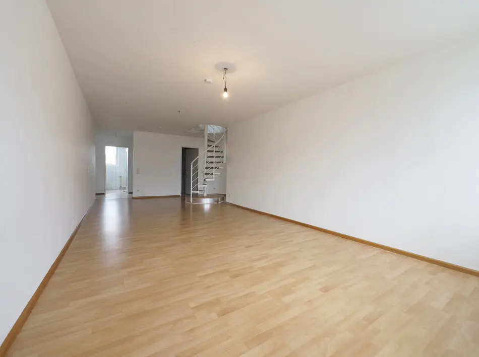 Empty room with light wood floors, white walls, and a white metal spiral staircase leading to an upper level.