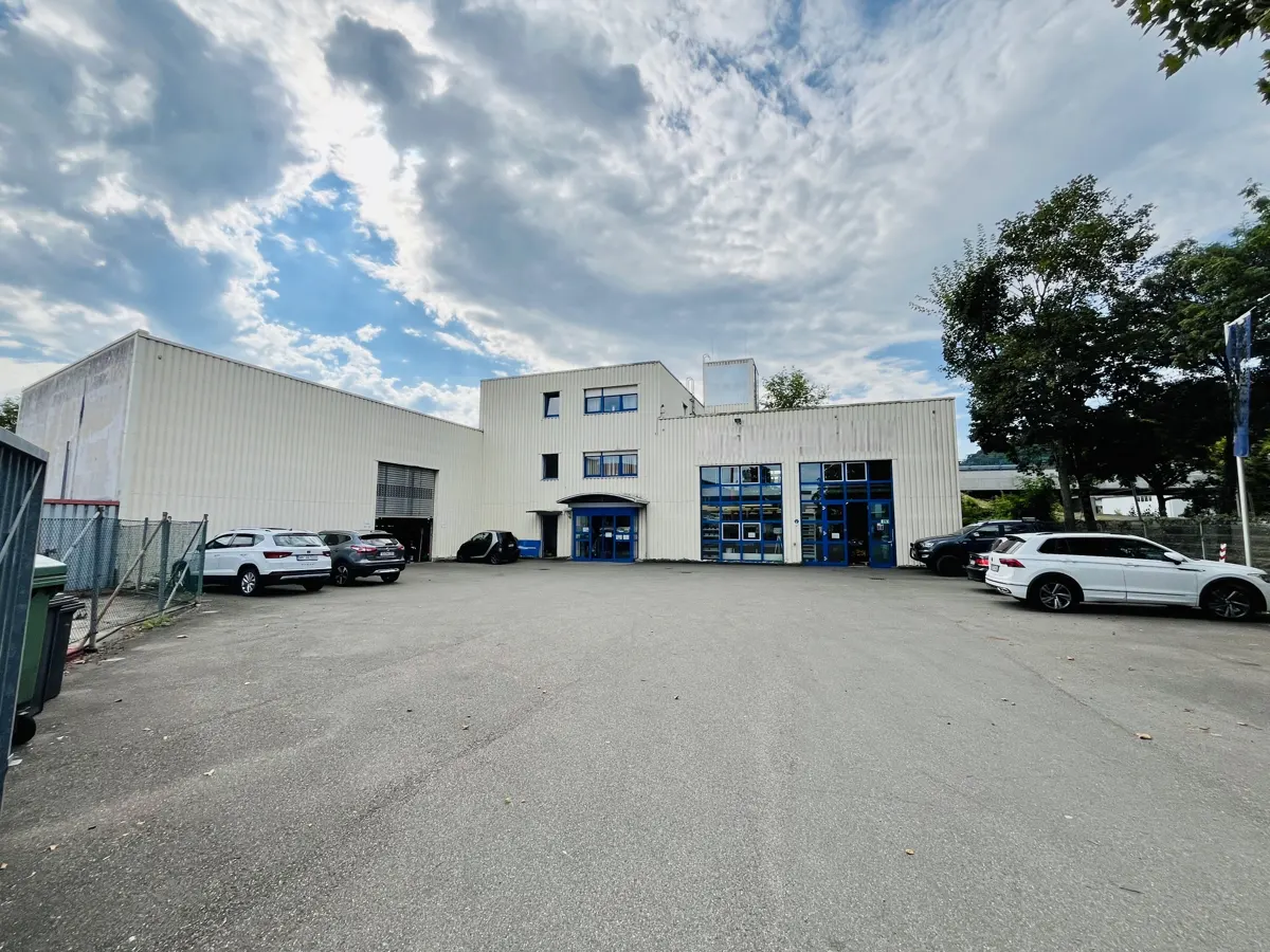 Exterior view of a white commercial building with blue trim and parked cars under a cloudy sky.
