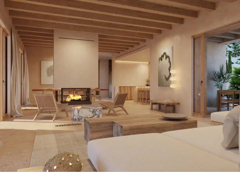 A bright living room with a fireplace, wooden beams, and neutral tones. A white sofa and wooden furniture are visible. Outside, there is a patio with greenery.