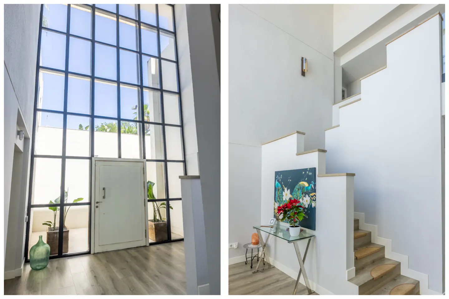 Modern entryway with floor-to-ceiling grid windows, white door, and a staircase with a glass console table and wall art.