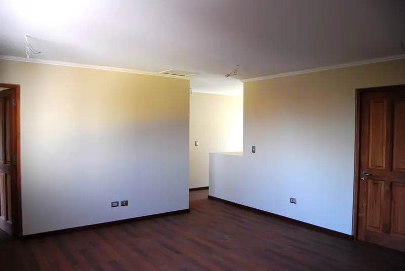 Empty room with dark wood floors, light yellow walls, and white trim. Two wood doors are visible.