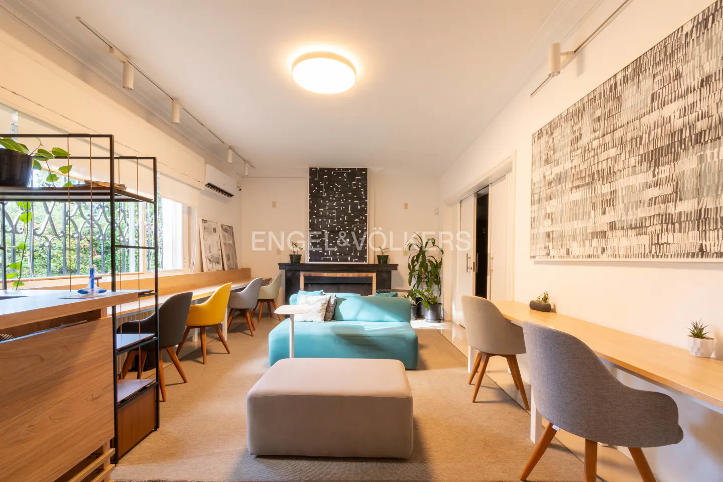 Bright, modern office space with a blue sofa, fireplace, and built-in desks. Artwork adorns the walls.