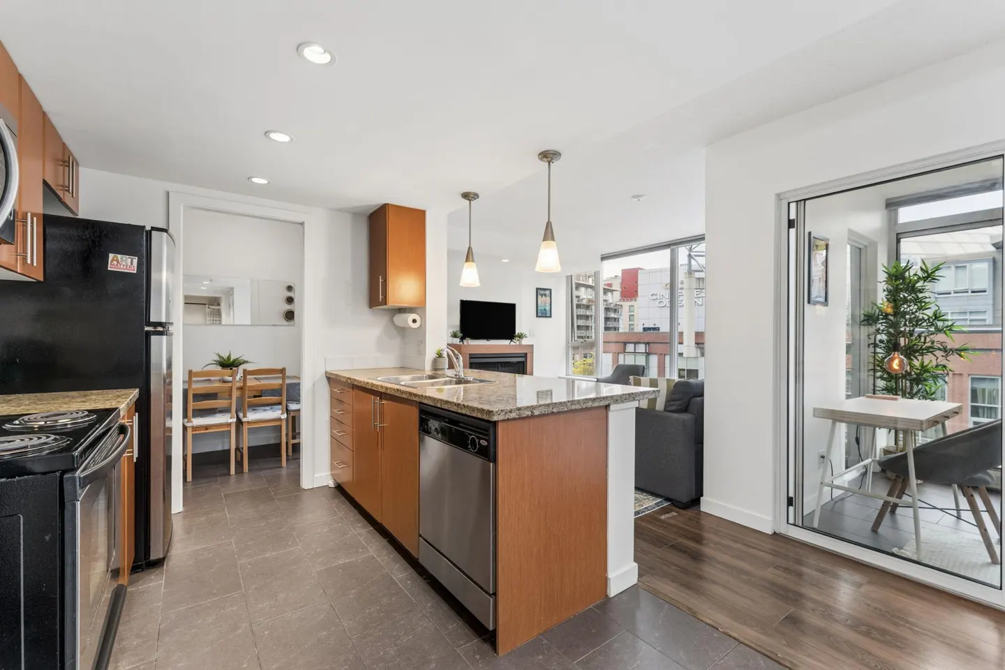 A modern condo interior with a kitchen island, stainless steel appliances, and a balcony with city views.