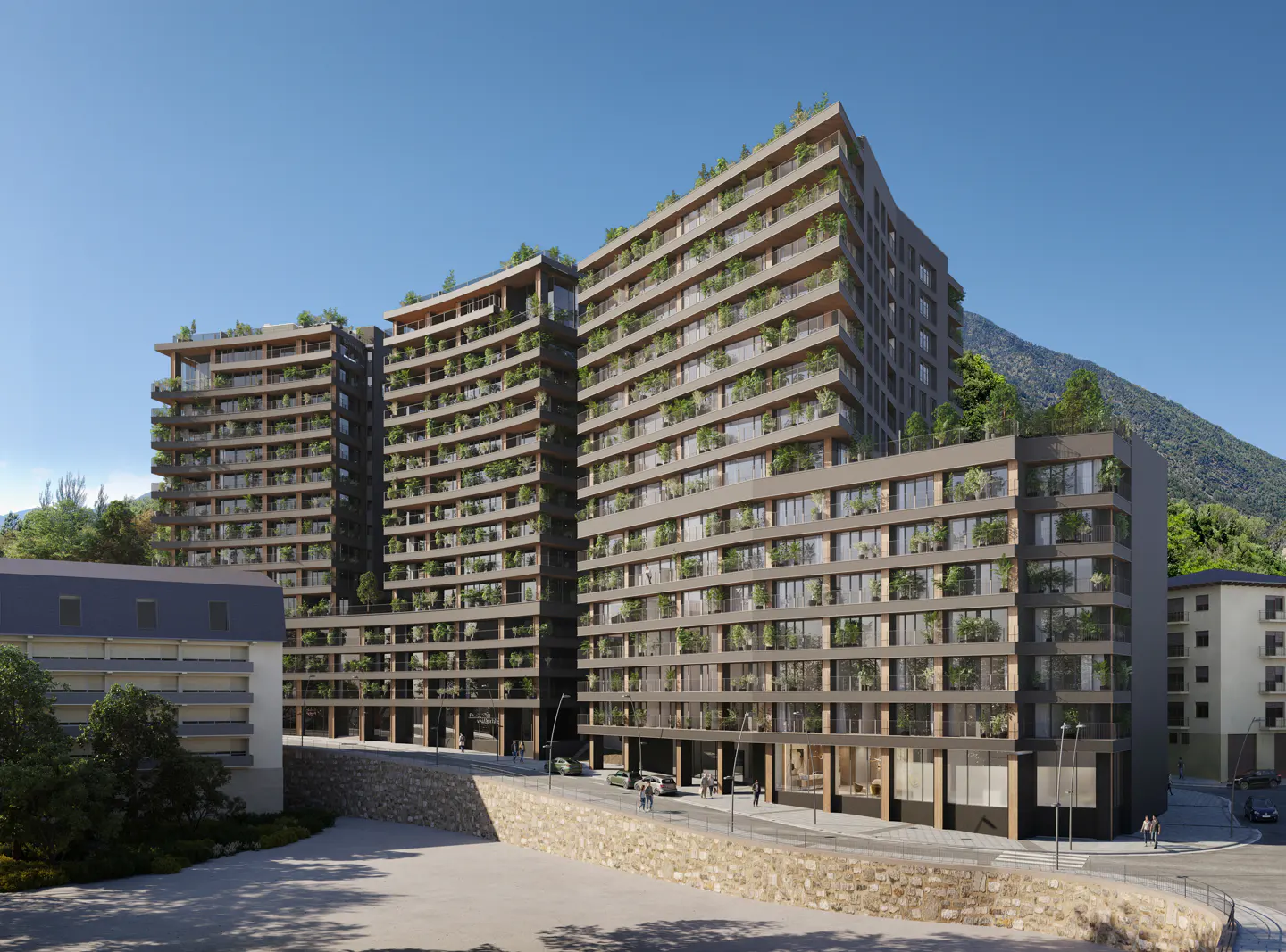 Modern apartment buildings with balconies and greenery, set against a mountain backdrop on a sunny day.