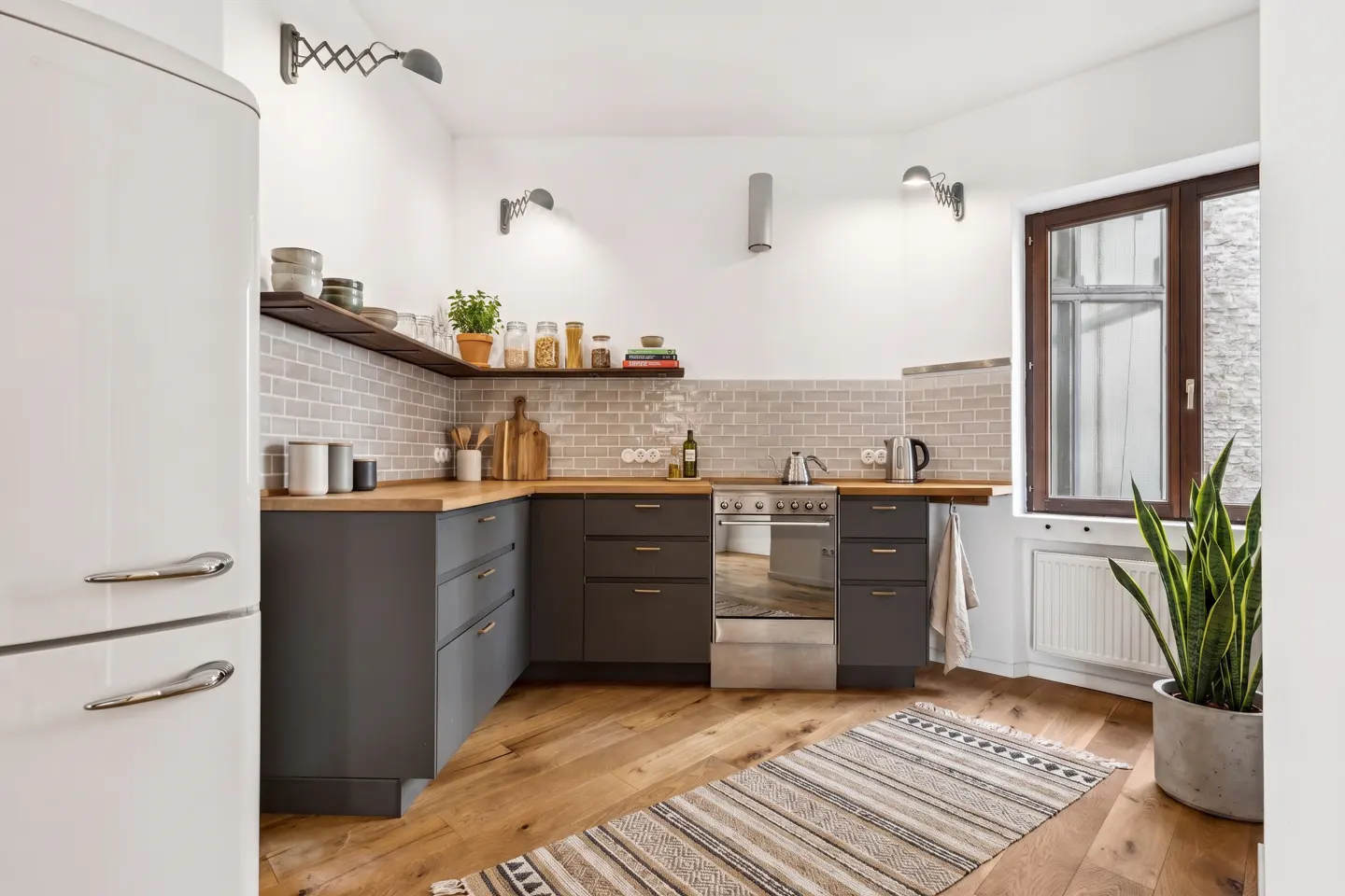 Modern kitchen with dark grey cabinets, wood countertops, white subway tile backsplash, and a white retro refrigerator.