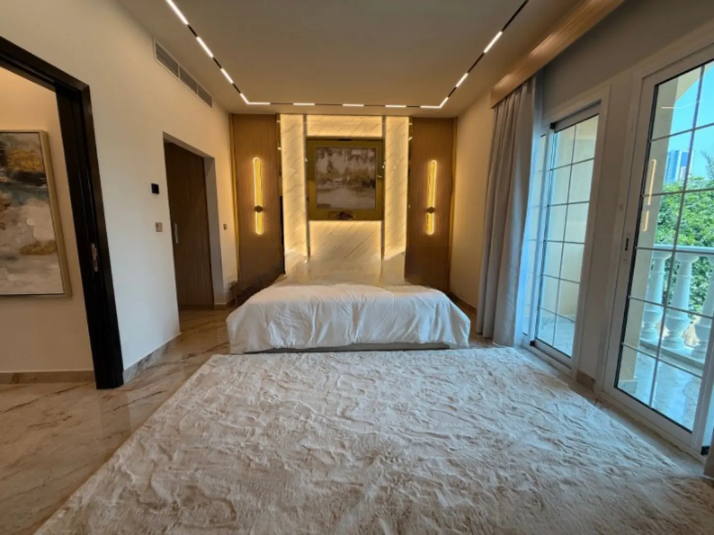Bedroom with a white bed, a large rug, and a view from the windows.