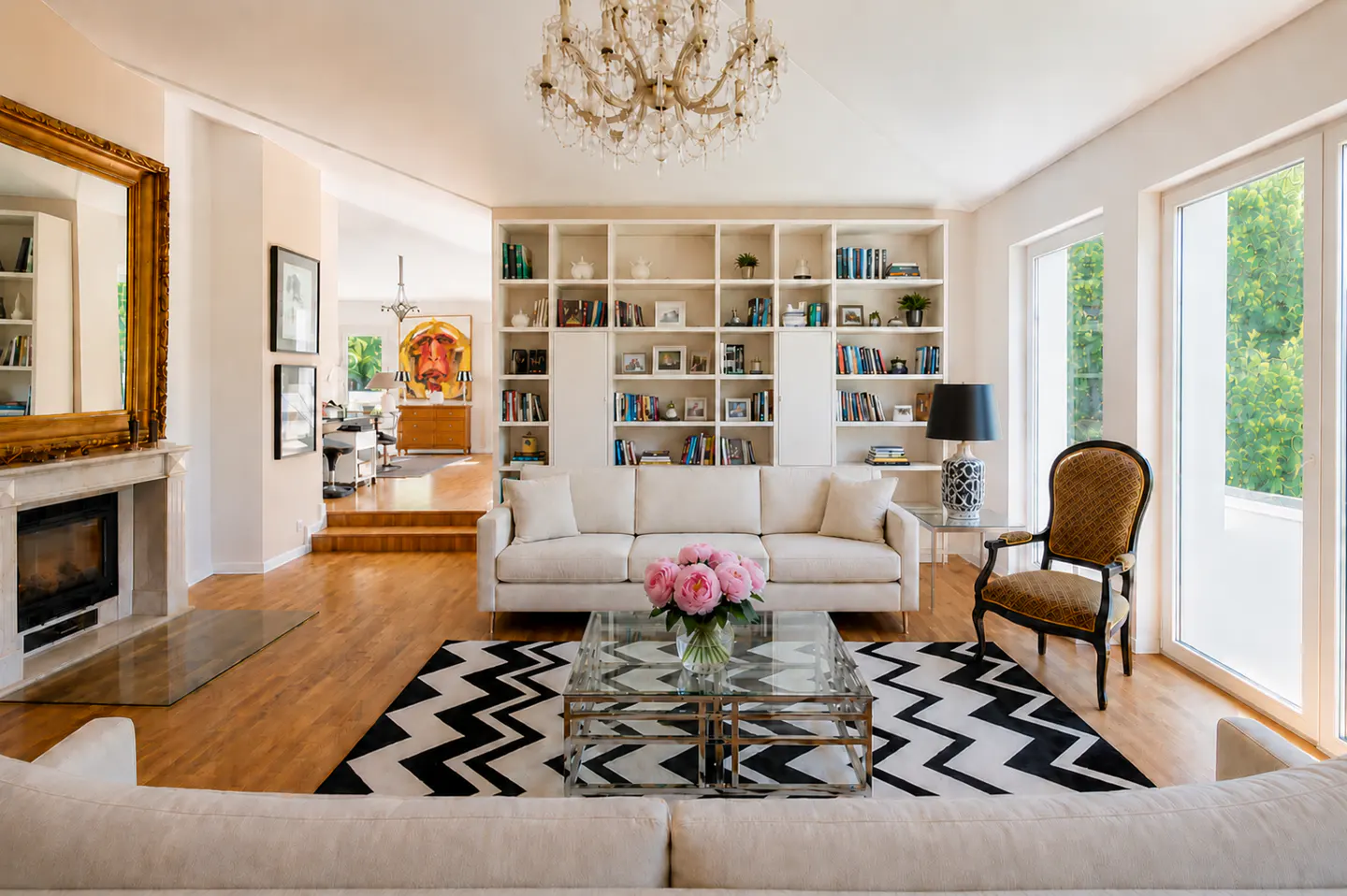 Elegant living room with a cream sofa, glass coffee table, pink flowers, and a black-and-white chevron rug.