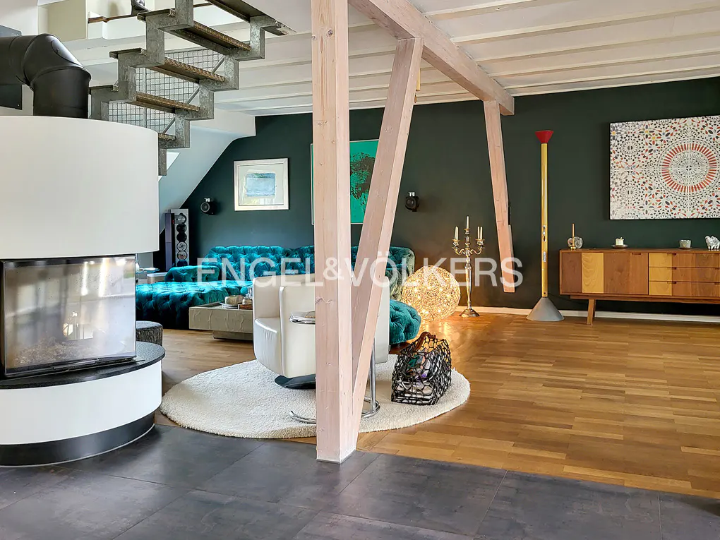 A modern living room with dark green walls, wooden floors, and a fireplace. A teal sofa and white chair sit on a white rug.