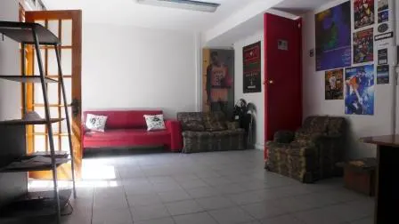 A living room with a red sofa, patterned armchairs, and posters on the wall.