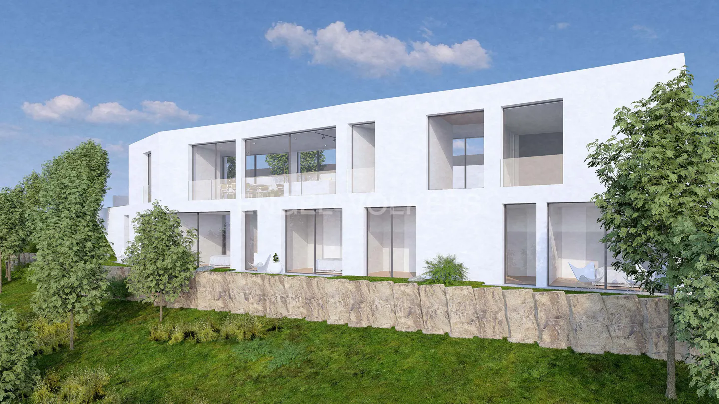 Modern white house with large windows on a grassy hill, trees on the sides, and blue sky.