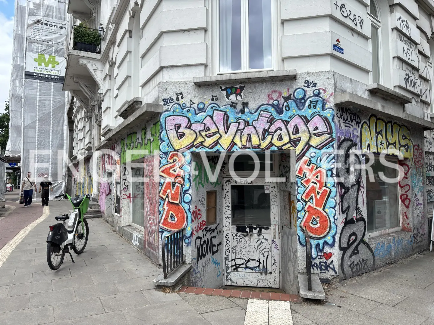 A corner storefront with colorful graffiti reading "Brevintage 2nd Hand" above a recessed entrance on a city sidewalk.