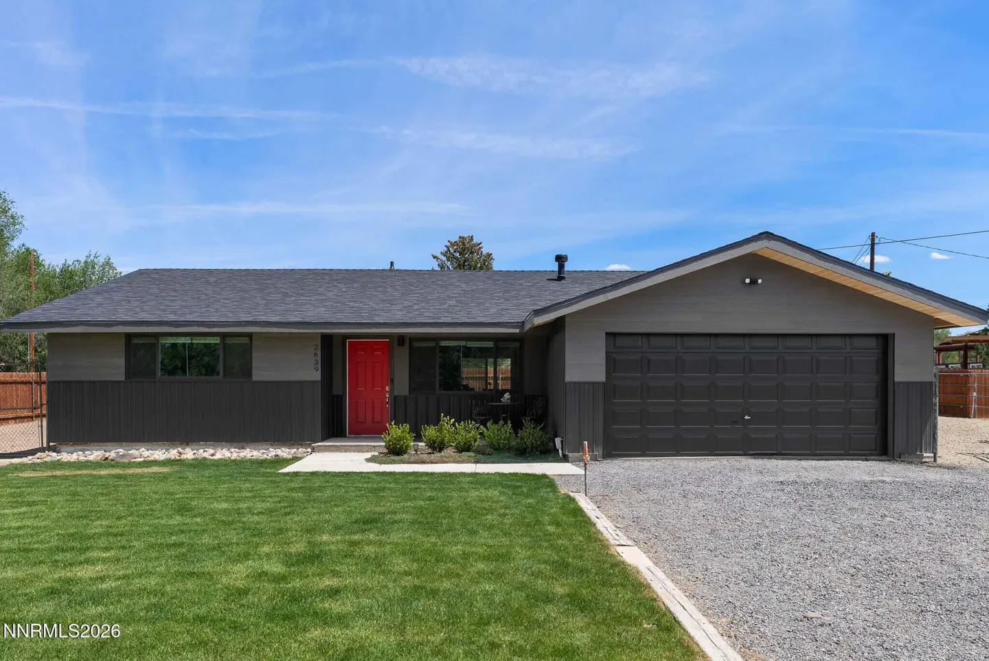 A single-story gray house with a red front door, a dark gray roof, and a green lawn.