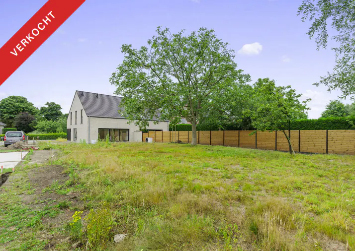 Sold house with a large yard, a wooden fence, and a big tree under a blue sky.
