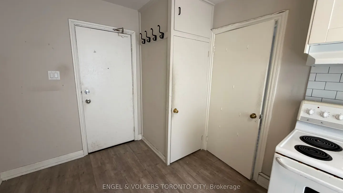 A corner of a kitchen with two white doors, a white cabinet, and a white stove.