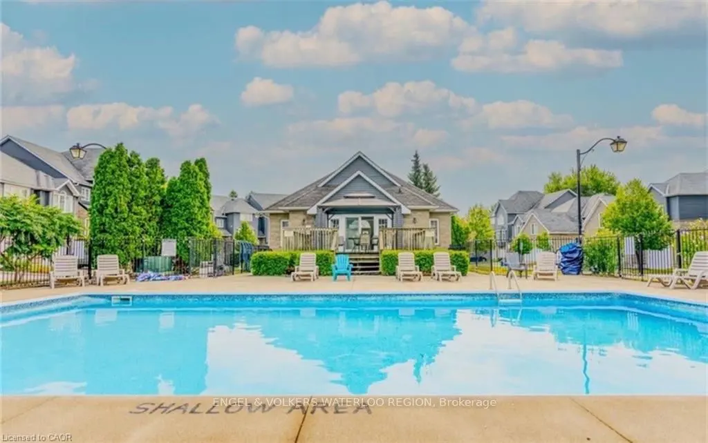 Outdoor pool with lounge chairs and a clubhouse in the background on a sunny day.