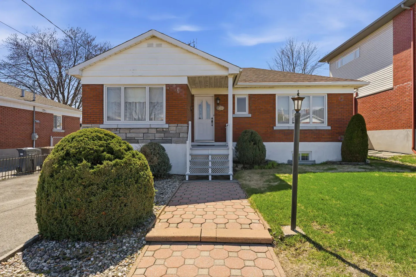 A single-story red brick house with a white door and trim, a stone accent, and a brick walkway leading to the entrance.