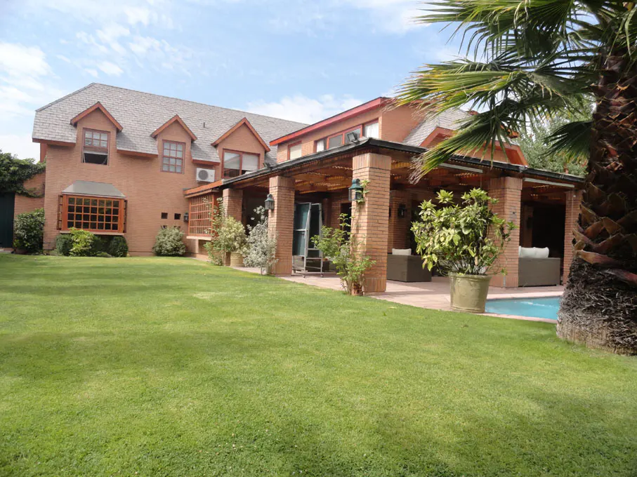 Brick house with a green lawn, patio, and pool. A palm tree is on the right side of the image.