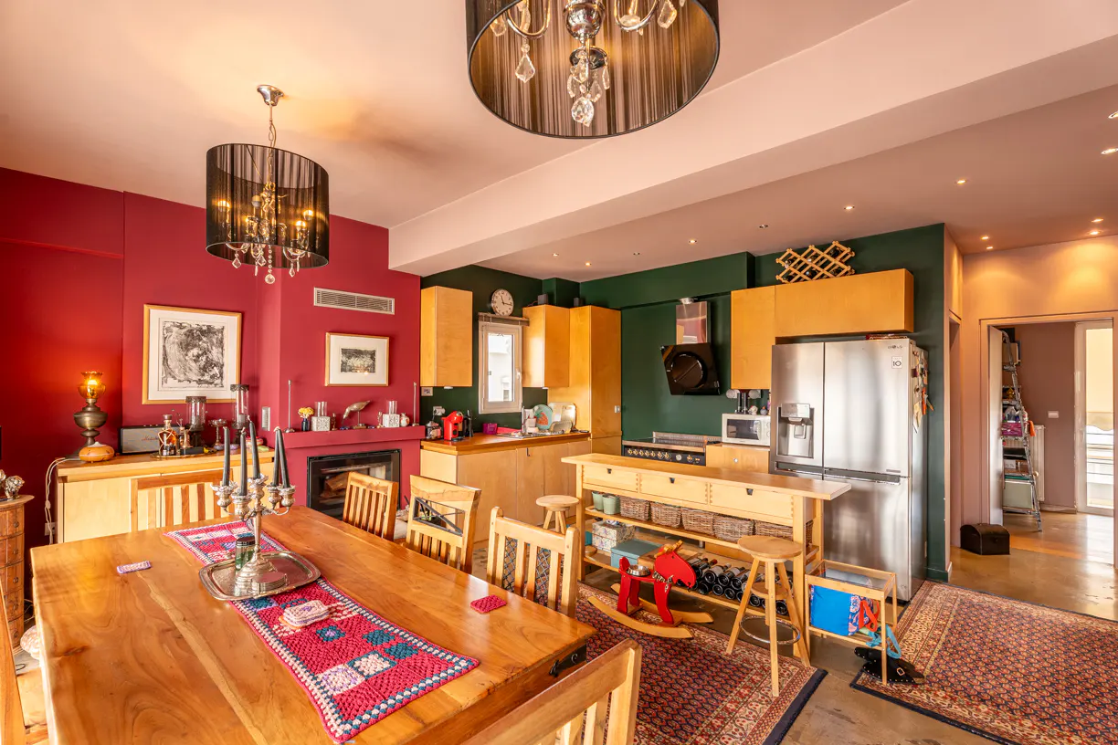 Open-concept kitchen and dining area with red and green walls, wood table, and stainless steel appliances.