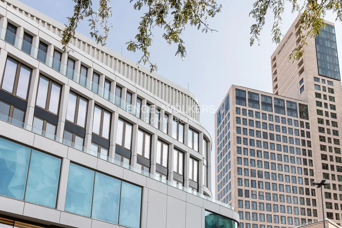 Modern office buildings with glass windows and white facades under a blue sky.