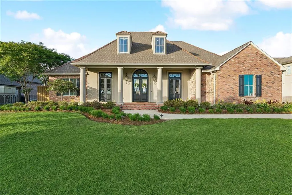 A single-story home with a green lawn, brick and stucco exterior, and a covered porch with columns.