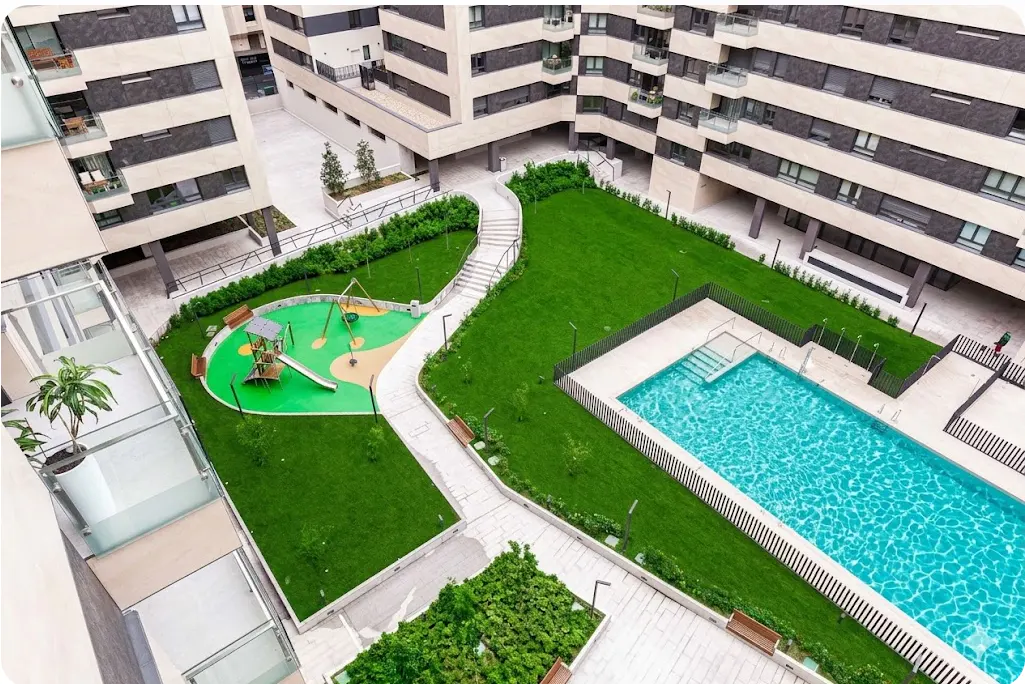Aerial view of a modern apartment complex with a pool, playground, and green spaces.