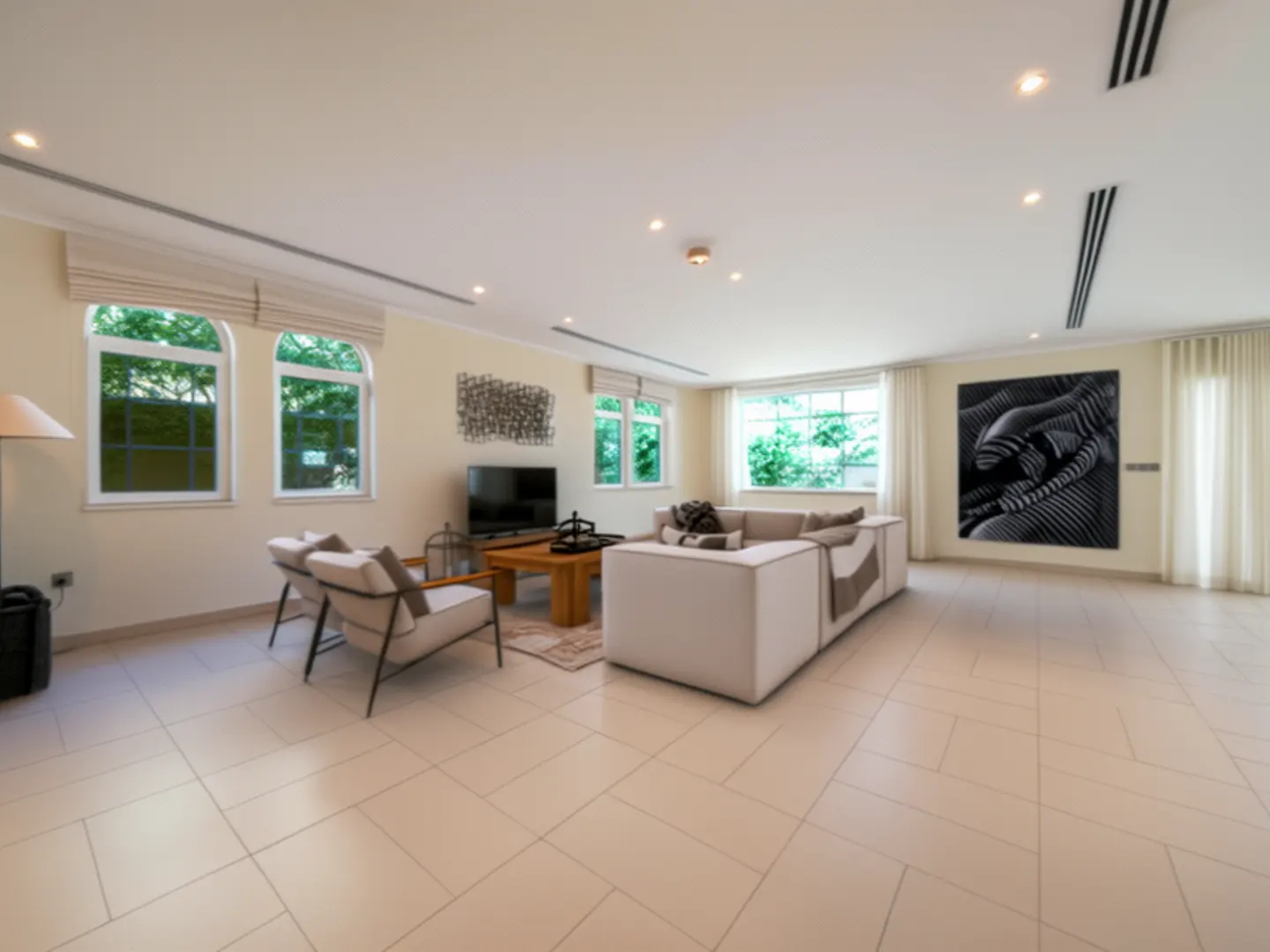 A bright living room with a white sofa, two chairs, a wooden table, and large windows.