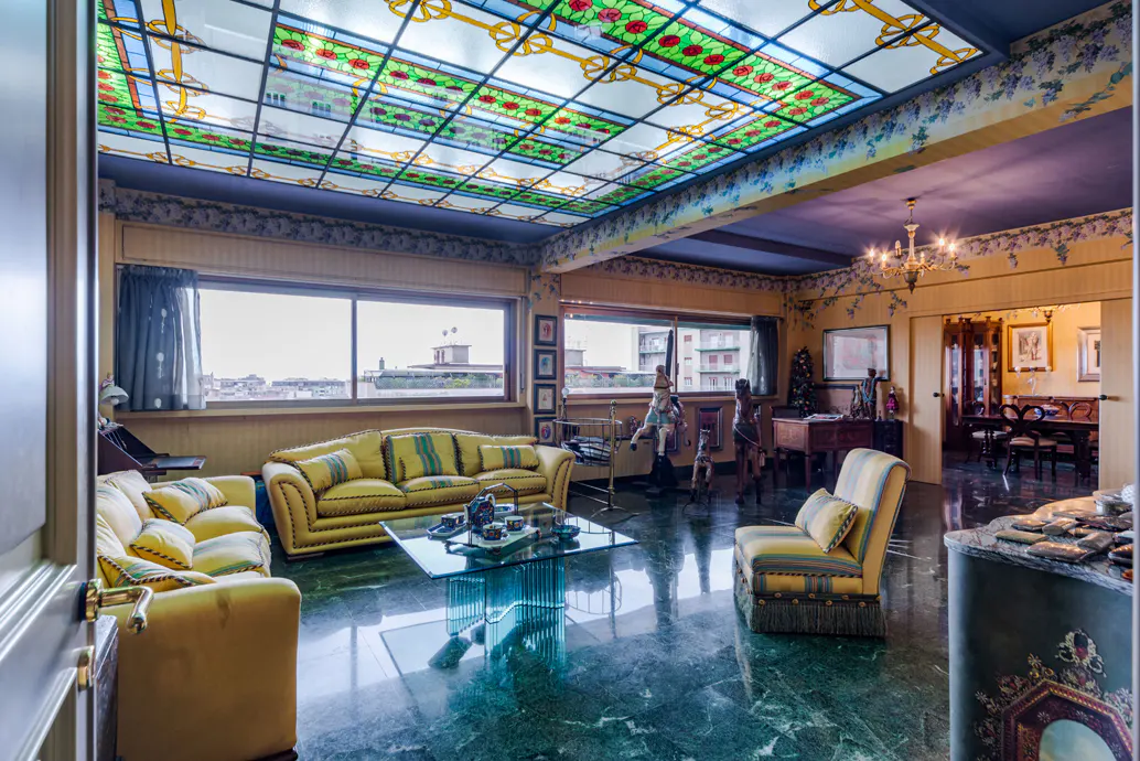 Living room with yellow sofas, green marble floor, and stained glass ceiling.