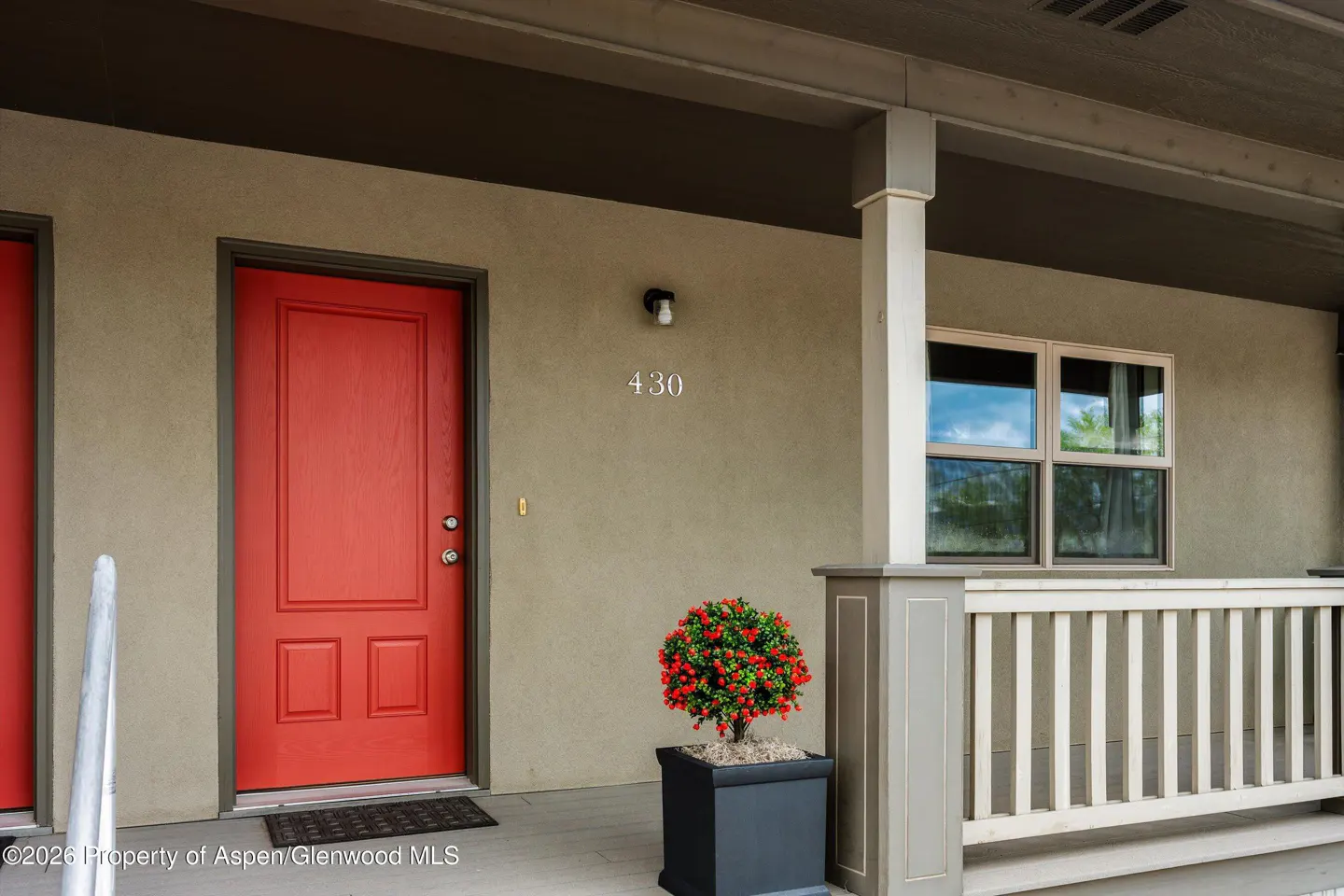 Exterior view of a condo with a red door, address number 430, and a small potted plant.