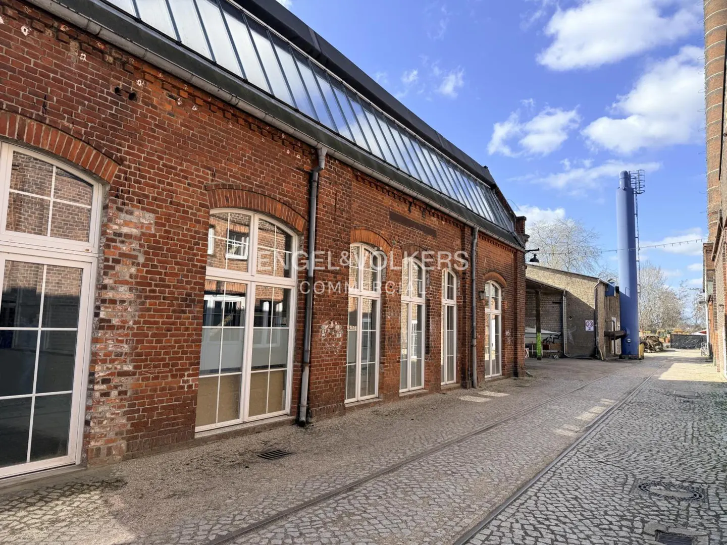 Exterior of a red brick commercial building with white framed windows and a glass roof.