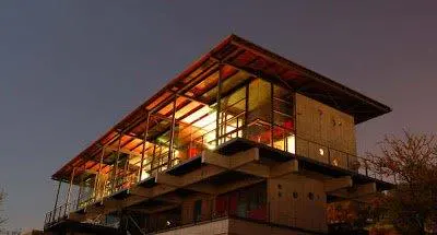 A modern, multi-story home with large windows and a flat roof at dusk.