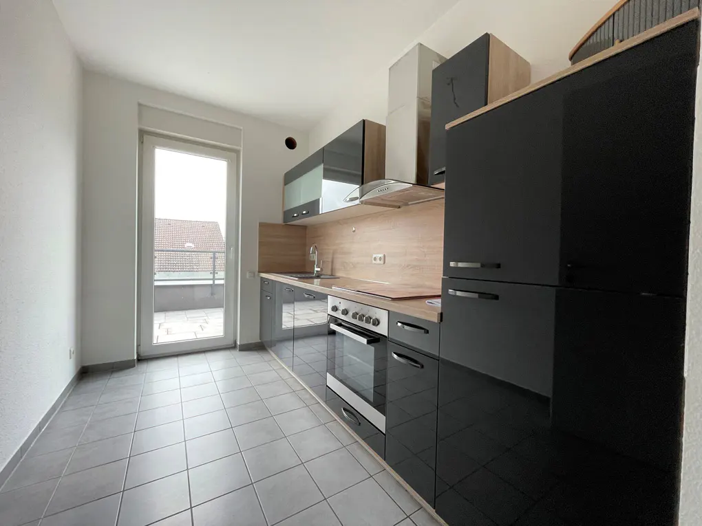 A modern kitchen with gray cabinets, stainless steel appliances, and a door to a balcony.
