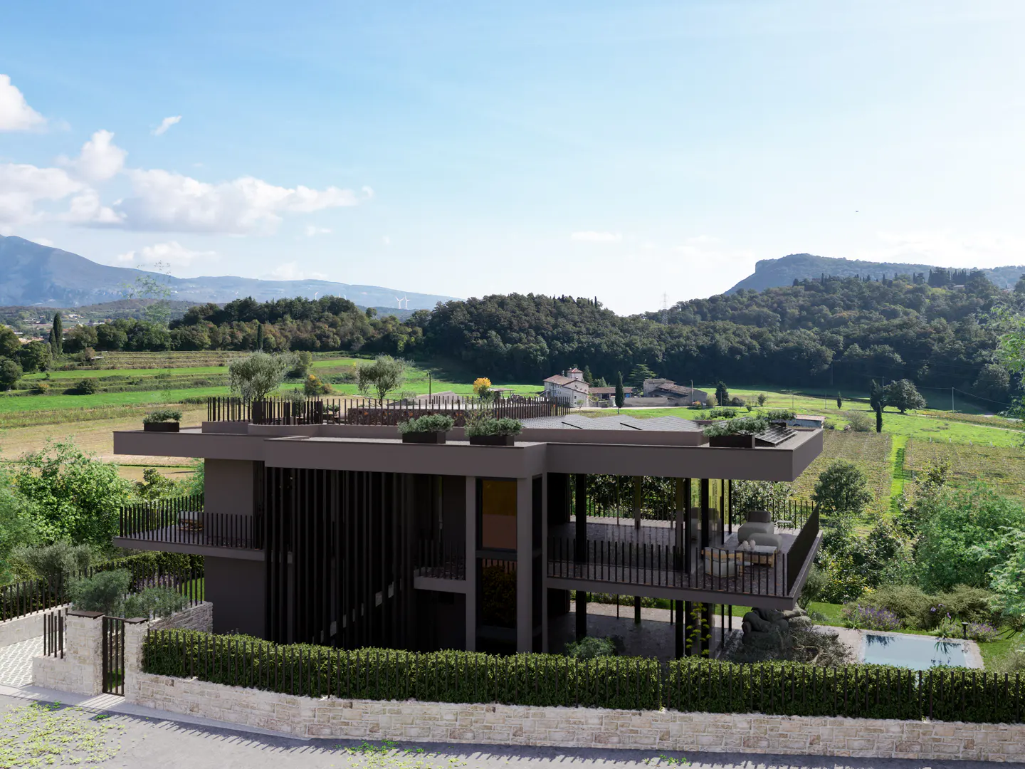 Modern two-story house with a flat roof and a balcony, surrounded by green trees and a stone wall. Mountains in the background.