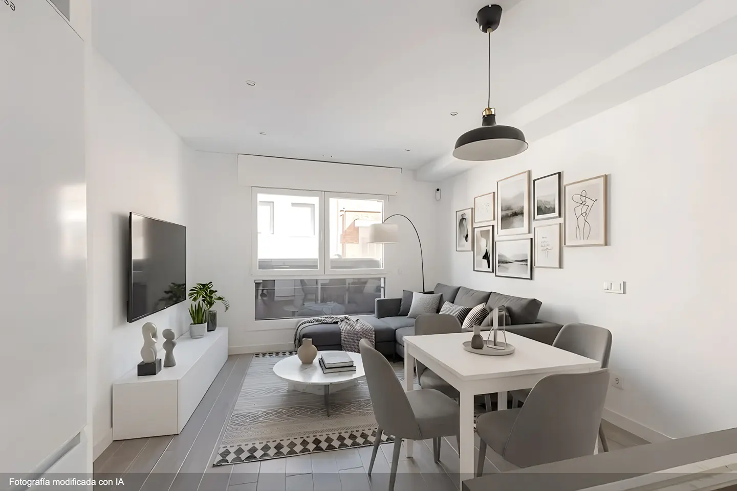 Modern living room with a grey sectional sofa, white dining table, wall art, and a large window with natural light.