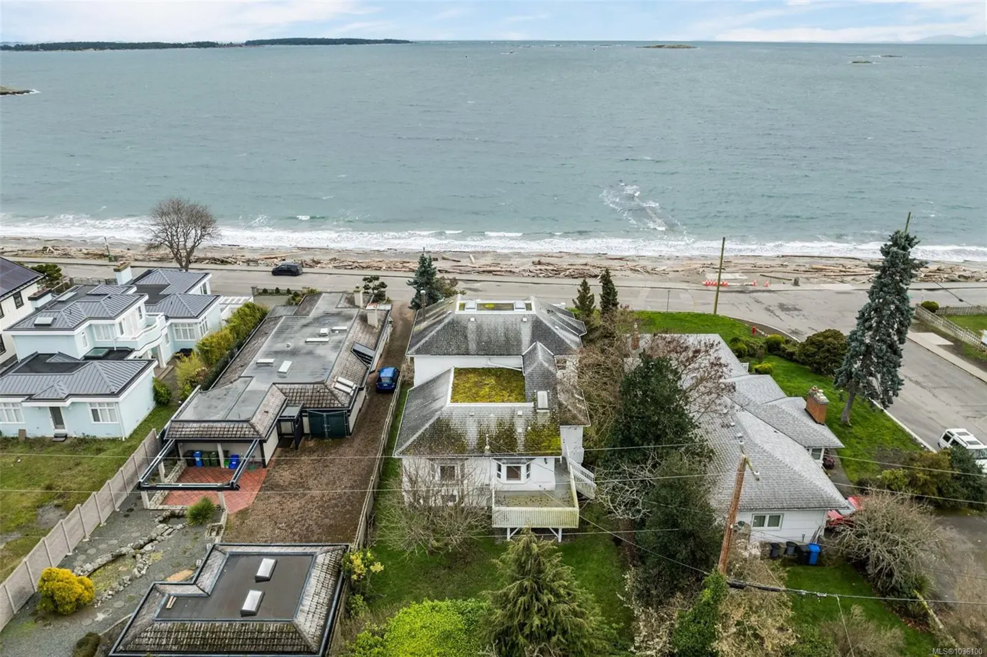 Aerial view of houses near the beach. The ocean is in the background. Overcast sky.
