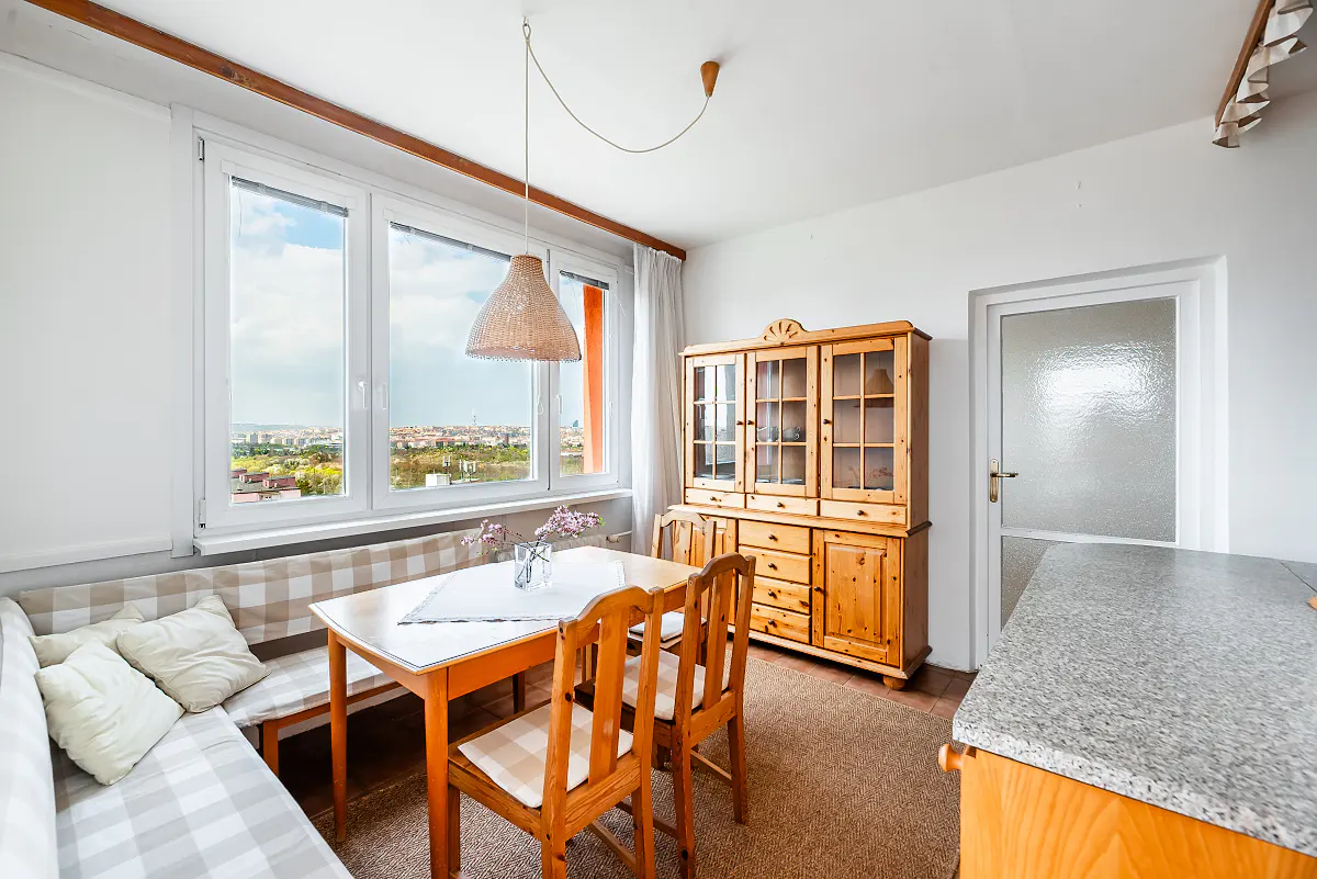 Bright dining area with a window view. A wooden table and chairs sit near a cushioned bench. A large wooden hutch stands against the wall.